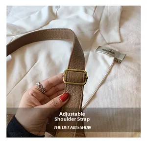 Close-up of adjustable brown leather shoulder strap with a gold metal buckle on a tote bag