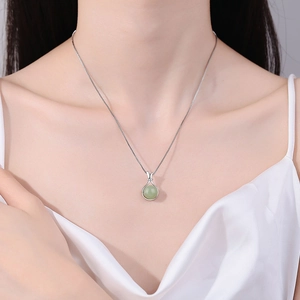 Elegant silver lucky bag necklace with light green gemstone pendant worn by a model
