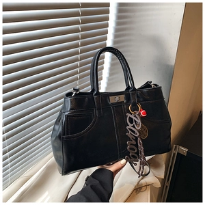 Close-up of black leather tote bag with silver turn-lock and Banog letter charm