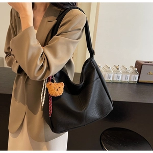Detail of black large capacity vintage tote bag featuring a cute brown plush bear charm