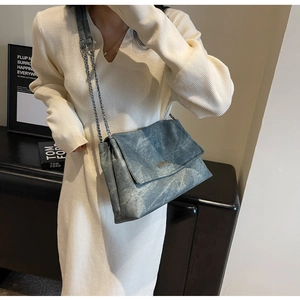 Detail of the blue denim texture and silver chain strap on this chic shoulder bag