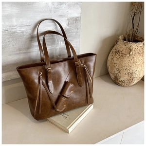 Detail view of vintage brown leather tote bag with gold buckle and small coin pouch