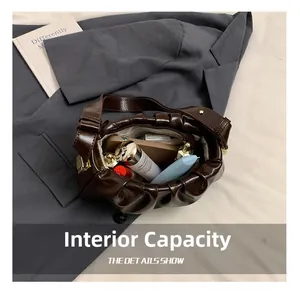 Spacious interior of brown pleated shoulder bag showing phone and cosmetics for daily use
