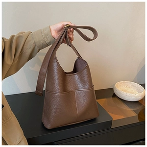 Detail of dark brown lychee textured leather tote bag with wide shoulder strap