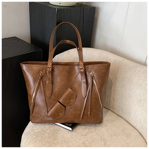 Detail of a brown leather tote bag with unique eyewear pouch and golden zippers