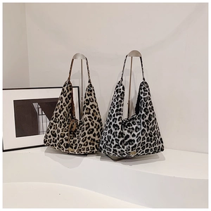 Detailed view of two leopard print plush tote bags with metal labels on a minimal stand