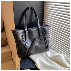 Close-up of black retro tote bag with golden zipper tassel and matching mini pouch detail