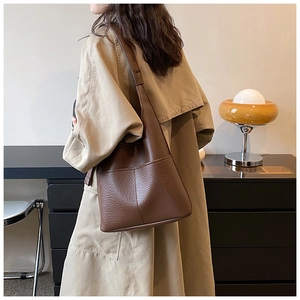 Detail of a large brown pebbled leather tote bag with wide shoulder strap and neat stitching