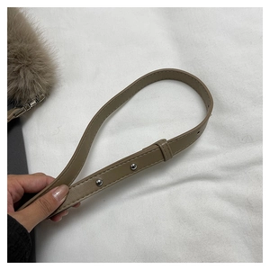 Detailed close-up of khaki leather shoulder strap with silver rivets and fluffy faux fur trim