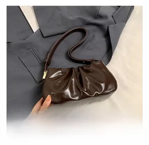 Detail of dark brown ruched cloud bag showing shiny faux leather texture and gold buckle