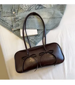 Close-up of a vintage dark brown leather underarm bag featuring dual bow knot decorations