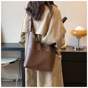 Detail of dark brown pebble leather hobo bag with front pockets and adjustable strap