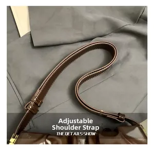 Detail of adjustable shoulder strap with gold buckle on a brown leather cloud bag