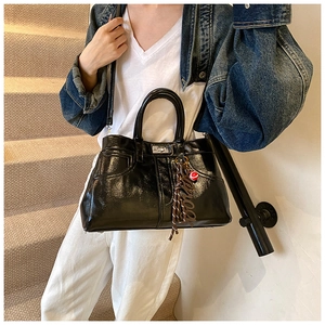 Close-up of black patent leather tote bag featuring metallic lock and detachable strap