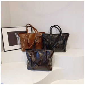 Three vintage tote bags in brown, black, and coffee colors on a minimalist display stand