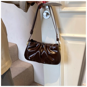 Detail of dark brown pleated cloud bag with shiny PU finish and golden metal buckles