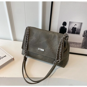 Detail of dark olive green shoulder bag showing vintage textured faux leather and chain