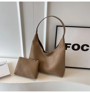 Detail of khaki woven tote bag with matching interior pouch on minimalist desk