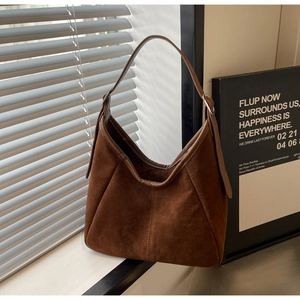 Macro shot of dark brown suede hobo bag detailing vertical stitching and metal buckle strap