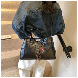 Detail of glossy black tote bag with denim pocket stitching and silver twist lock detail