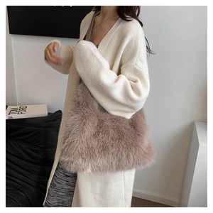 Detail of plush faux fur shoulder bag in dusty rose styled with a cream knit cardigan