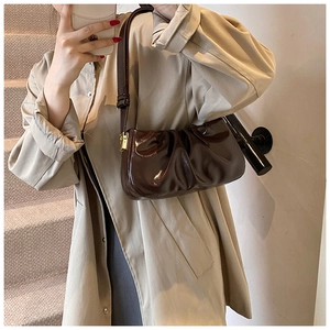 Macro detail of dark brown cloud pleated underarm bag in glossy leather with gold hardware