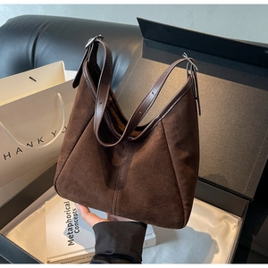 Detail of dark brown matte suede hobo bag featuring vertical stitching in a gift box
