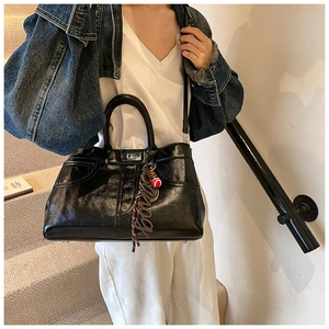 Detail of glossy black vintage tote bag with silver rotary lock and stylish charm