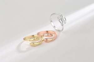Detailed close-up of three polished hugging hands open rings in gold, silver, and rose gold