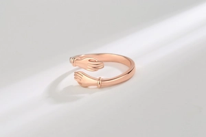Macro shot of rose gold hugging hands ring showing high-polish finish and detail