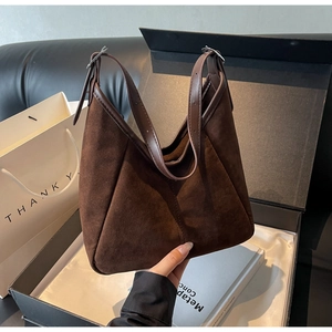 Detail of dark brown faux suede tote bag with adjustable leather strap and side stitching
