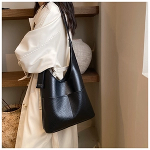 Close-up of black lychee grain leather tote bag with dual front pockets and adjustable strap
