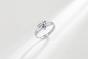 Macro detail of rotating silver-toned ring with heart-shaped purple stone and pavé accents