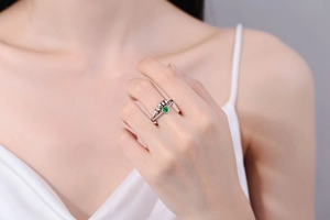 Detail of a rotating stress relief ring with green heart gemstone and silver sliding beads