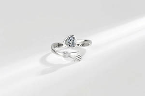 Macro detail of 'I love forever' engraving and heart-shaped zircon on hugging hands ring