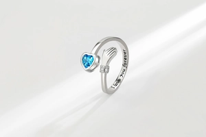 Macro shot of silver hugging ring with blue heart stone and I love you forever engraving