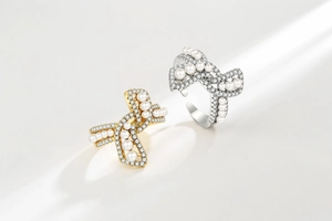 Close-up of gold and silver bow rings with sparkling pavé crystals and white pearls