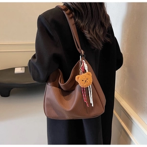 Detailed shot of large brown leather tote bag with a cute bear charm on shoulder