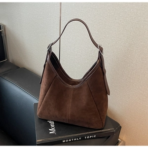 Close-up of matte brown suede hobo bag with vertical stitching and silver buckle detail