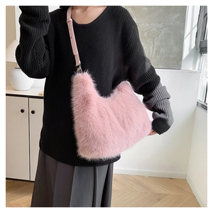 Pink faux fur hobo bag with leather strap shown in a stylish shoulder carry pose