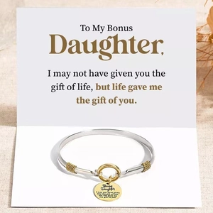 Bracciale Bonus Daughter con ciondolo dorato e biglietto su sfondo materico