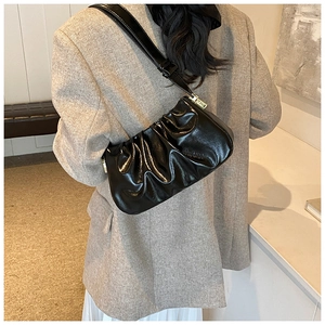 Detail showing high-gloss black patent leather pleats and texture on the shoulder bag