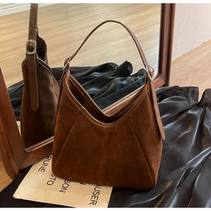 Detail of adjustable leather strap with silver buckle on brown suede tote bag