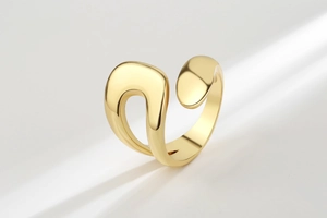 Macro detail of irregular glossy 18K gold ring with organic sculptural design and shadows