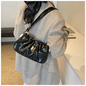 Detail of black glossy pleated cloud baguette bag with premium patent leather finish