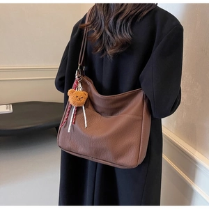 Brown faux leather hobo bag with a cute bear charm shown on a model's shoulder