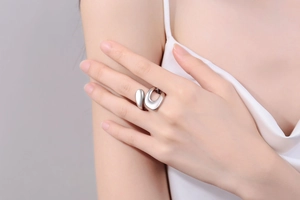 Close-up of minimalist silver irregular fluid ring on finger with polished metal texture