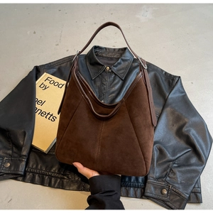 Detail view of the dark brown suede texture and leather handle on the oversized tote bag