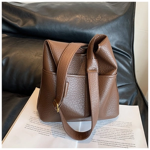 Close-up of deep brown lychee grain faux leather texture and vintage gold metal buckle