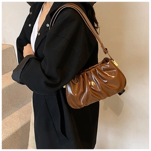 Detail view of dark brown pleated cloud bag with glossy finish and adjustable strap